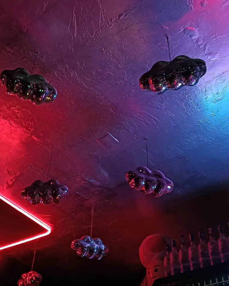 Nuvole di palle da discoteca appese al soffitto, illuminate di rosso e blu